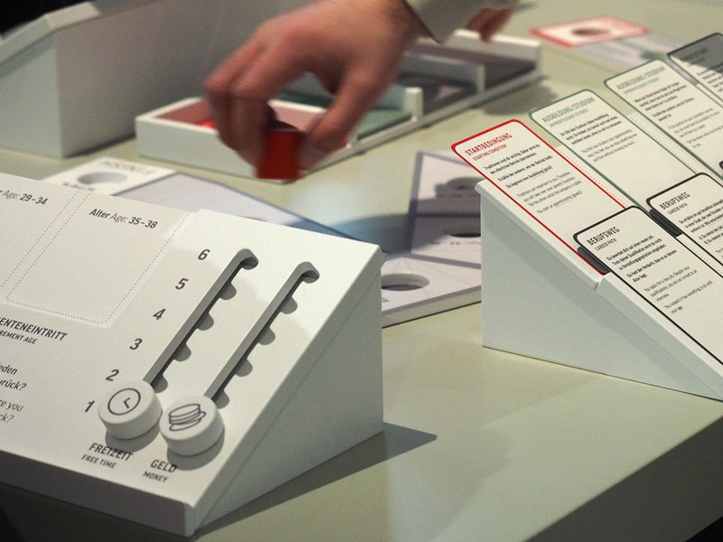 Ein Regler am Spieltisch zeigt an, wie sich die berufliche Karriere auf Freizeit und Geld auswirkt.